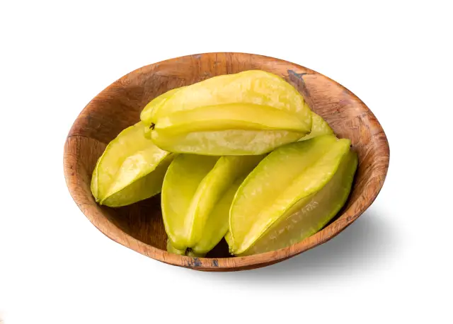 Pieces of yellow starfruit flesh in a wooden bowl.