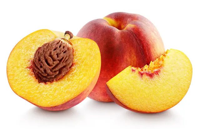 A whole peach next to a cut in half peach.