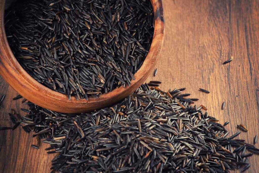 Wild rice in a bowl on a wooden surface.