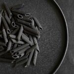 Dry black bean pasta on a black plate.