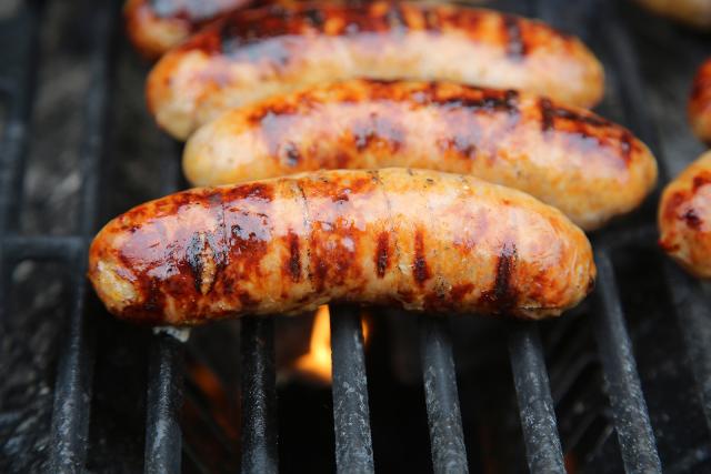 Four cooked pork sausages on the grill.