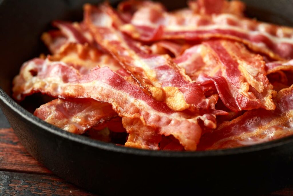 Grilled crispy bacon slices in a pan.