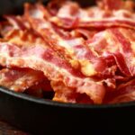 Grilled crispy bacon slices in a pan.