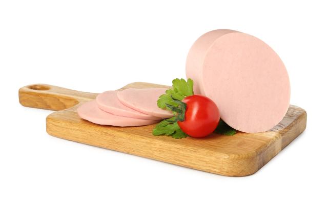 Luncheon sausage with several slices cut off on a wooden board.