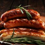 A pile of cooked sausages on a wooden surface.