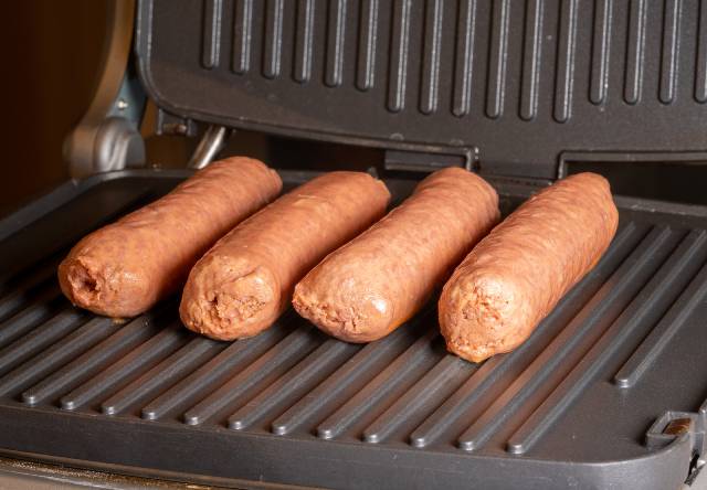 Plant-based sausages on a grilling machine.