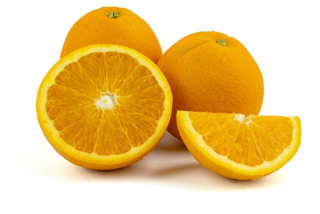 Whole and cut-in-half fresh navel oranges.