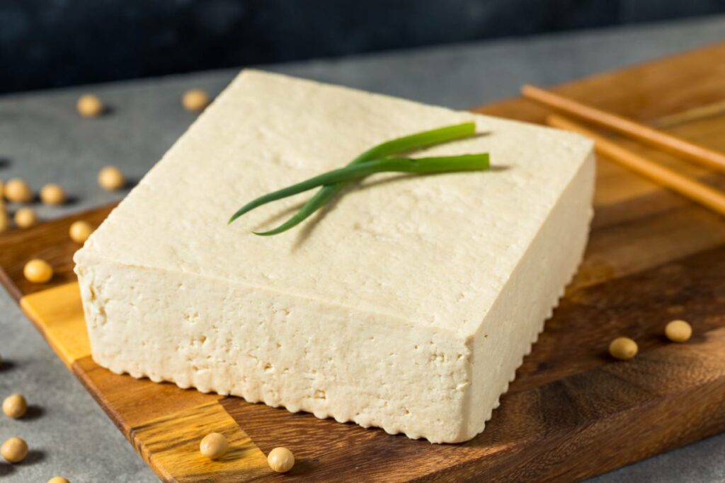 A block of extra firm tofu on a wooden board.