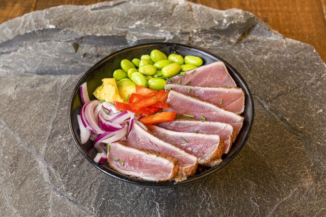 Cooked bluefin tuna in a black bowl.