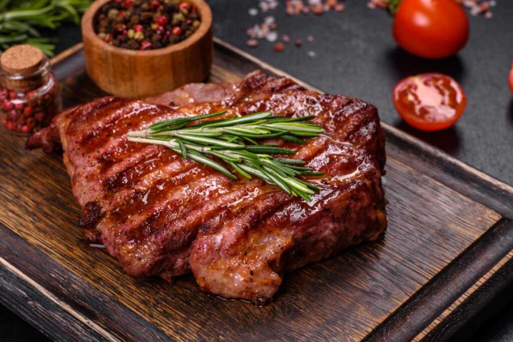 A cooked beef steak on a wooden plate.