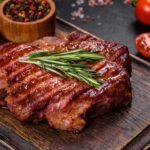 A cooked beef steak on a wooden plate.