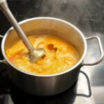 Pureeing cooked food in a cooking pot with an immersion blender.