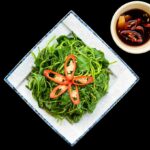 Stir-fried sweet potato leaves on a square-shaped plate.