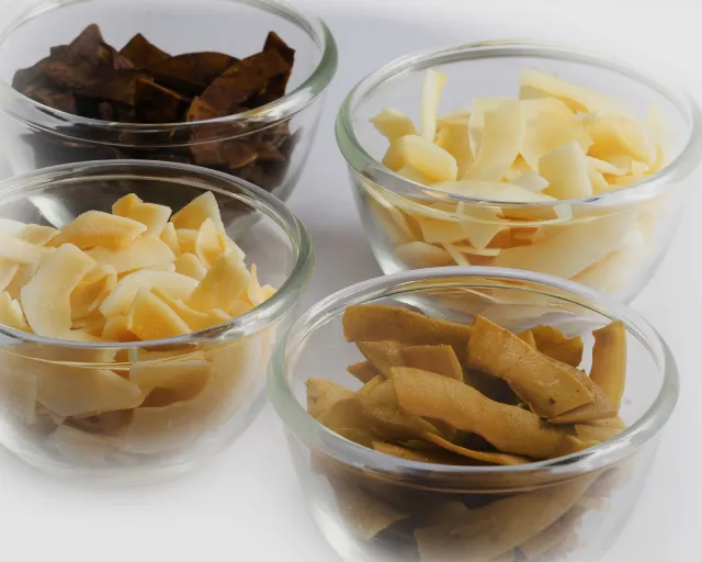 Various flavors of toasted coconut chips in separate glass bowls.