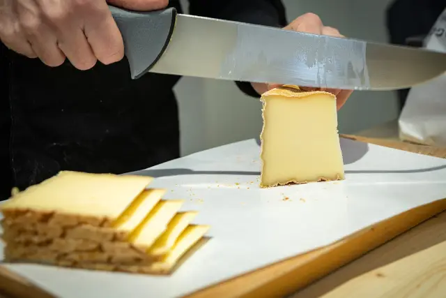 Portion of Vacherin Fribourgeois being cut into slices.