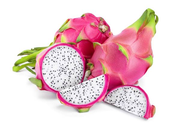 A whole dragon fruit next to sliced pieces.