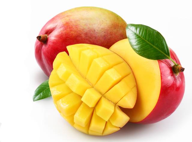 A whole mango next to a sliced mango.