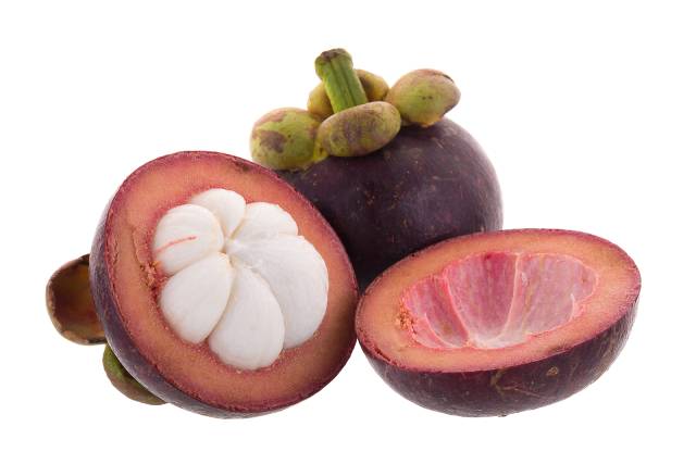 A whole mangosteen next to two halves of the fruit.