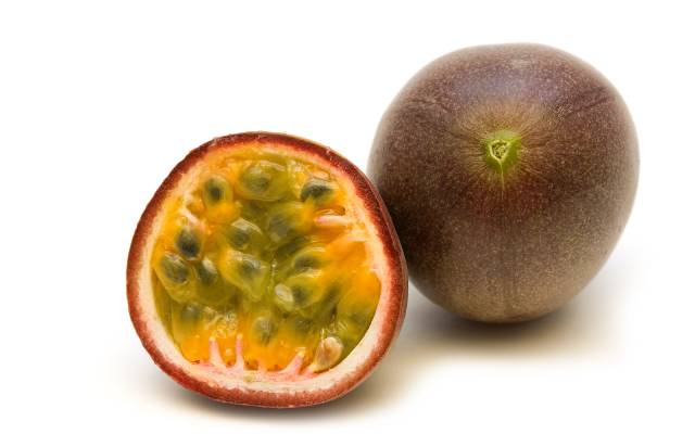 Whole passionfruit next to half a passionfruit showing its inner flesh.