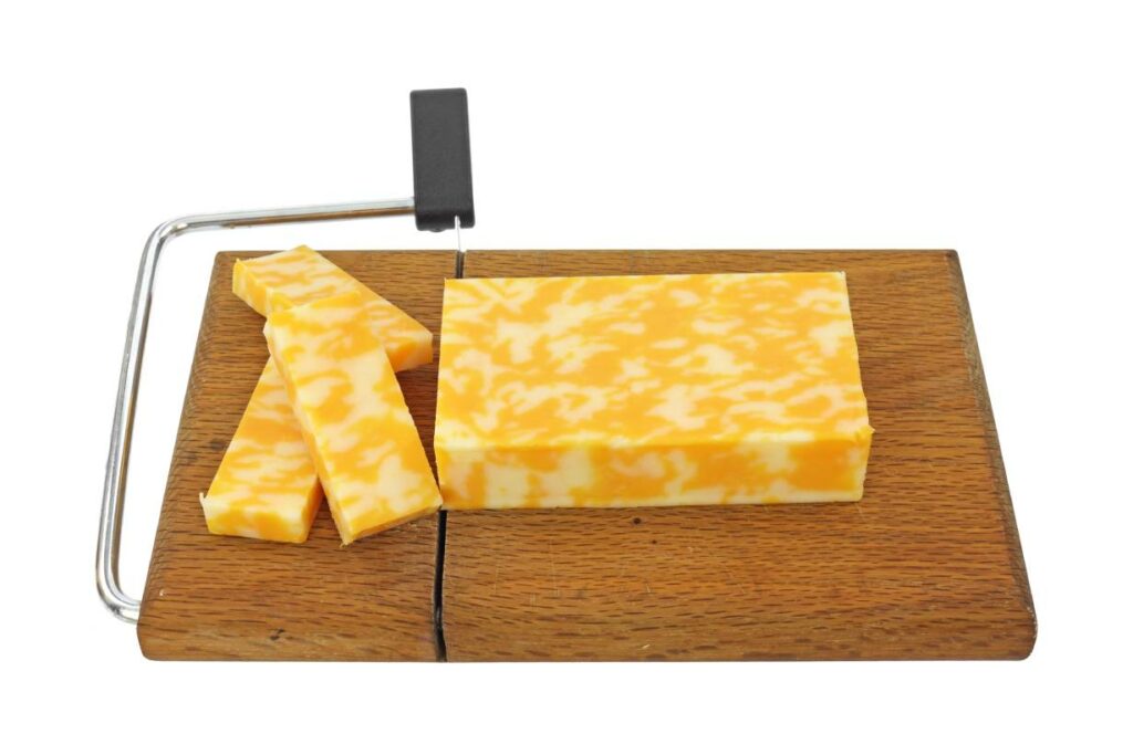 A large block of Colby Jack cheese on a chopping board.
