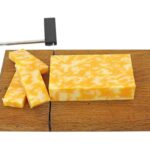 A large block of Colby Jack cheese on a chopping board.