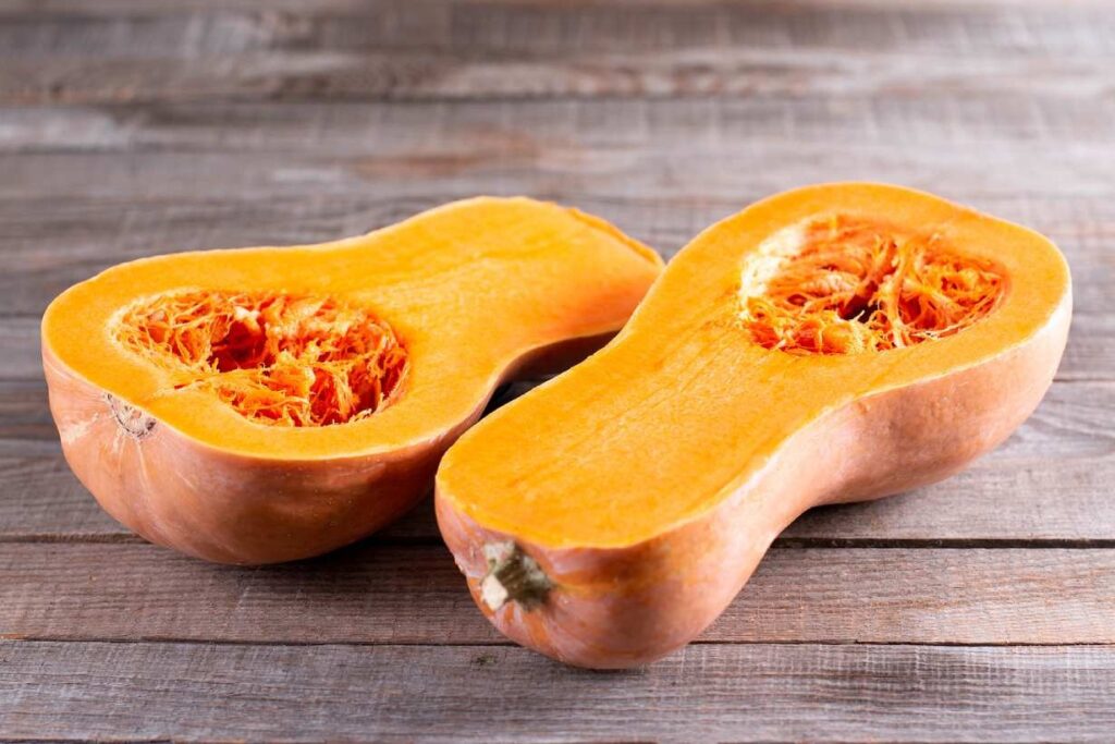 Two butternut squash halves on a wooden surface.