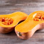 Two butternut squash halves on a wooden surface.