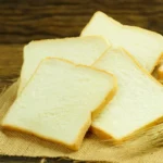Slices of white bread on a wooden surface.