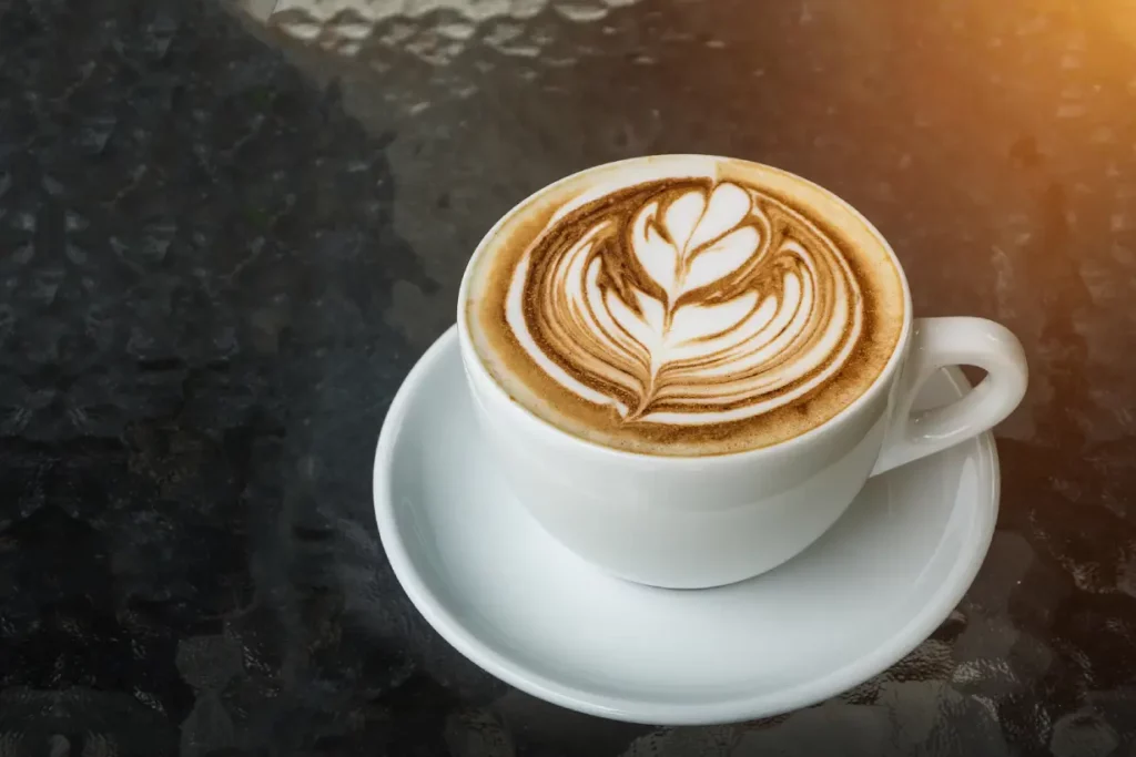 A white cup of hot latte on a white saucer.