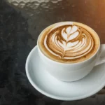 A white cup of hot latte on a white saucer.