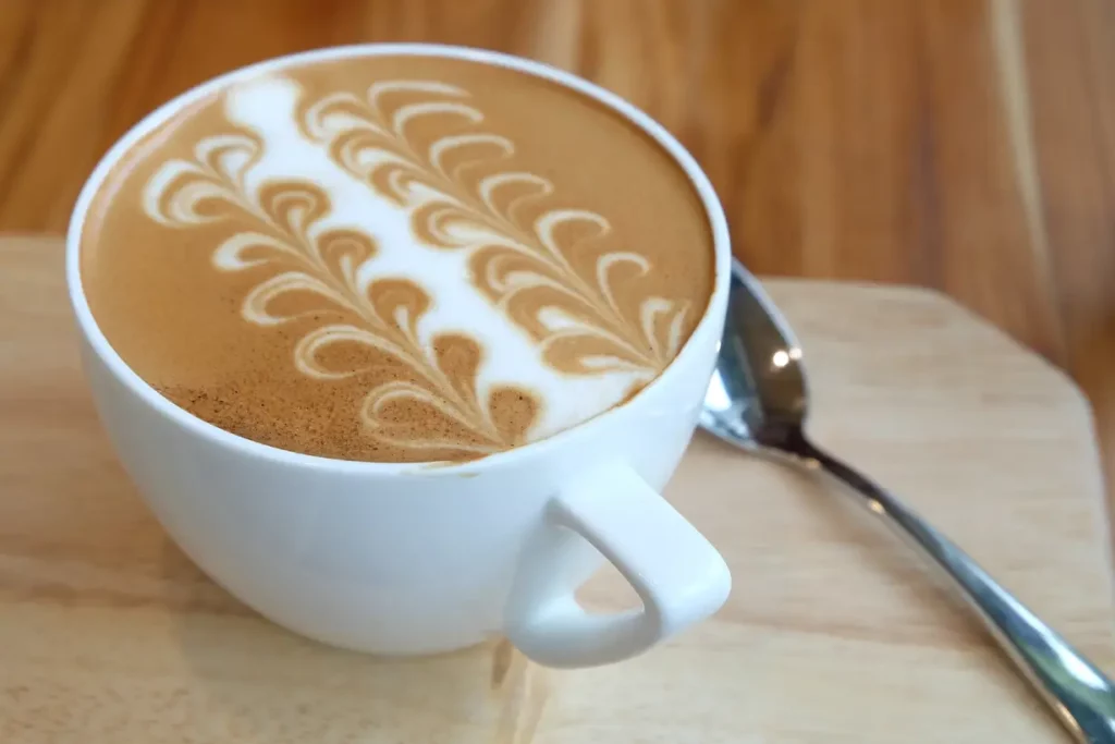 A big white cup of caffe latte with latte art on the surface.