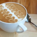 A big white cup of caffe latte with latte art on the surface.