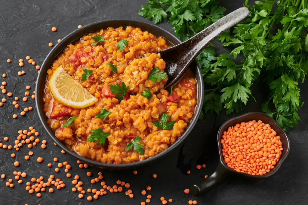 A bowl of cooked red lentils and a bowl of raw red lentils.