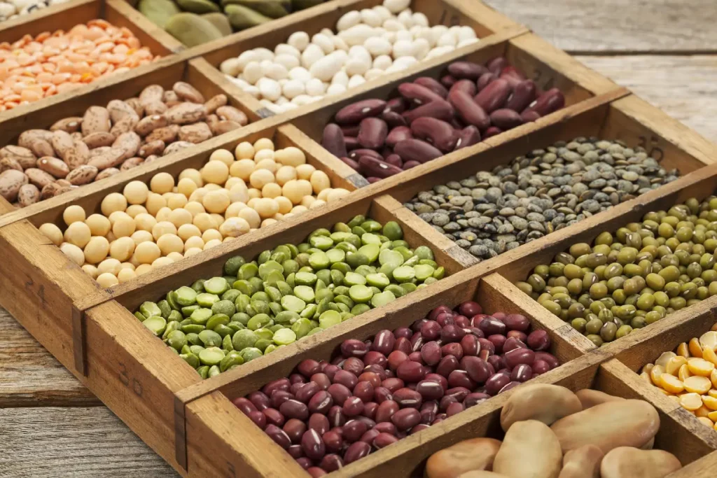Many different legumes in a wooden compartment tray box.