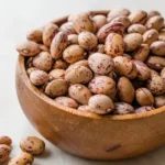 Raw, dried pinto beans in a wooden bowl.