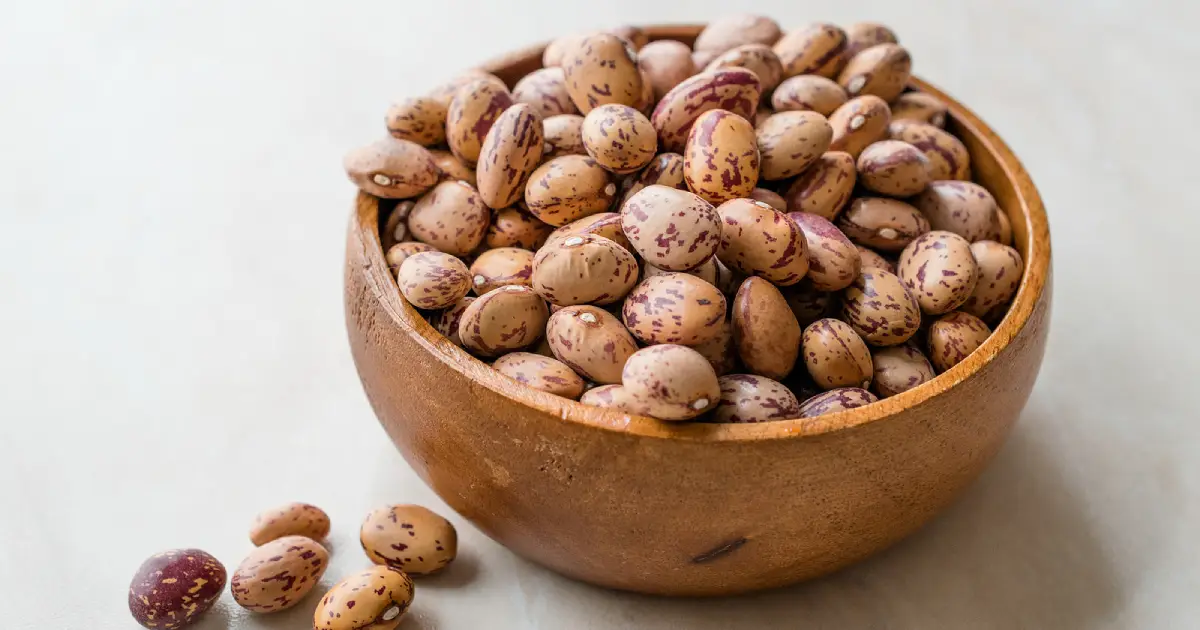 Raw, dried pinto beans in a wooden bowl.