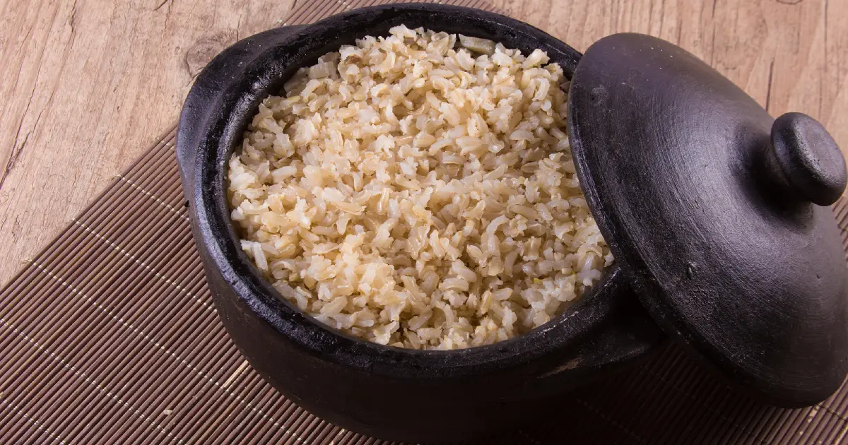 Cooked whole grain brown rice in a black ceramic pot.