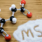 Monosodium glutamate (MSG) powder next to its chemical structure.