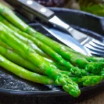 Asparagus: Nutrition Profile, Potential Benefits, and More Cooked asparagus spears on a black plate.