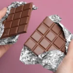 Milk Chocolate: Nutrition Profile, Benefits, and Drawbacks Two hands holding two halves of a milk chocolate bar.