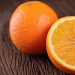 Key Health Benefits of Oranges (With Full Nutritional Properties) A whole, fresh navel orange next to a half piece of orange.