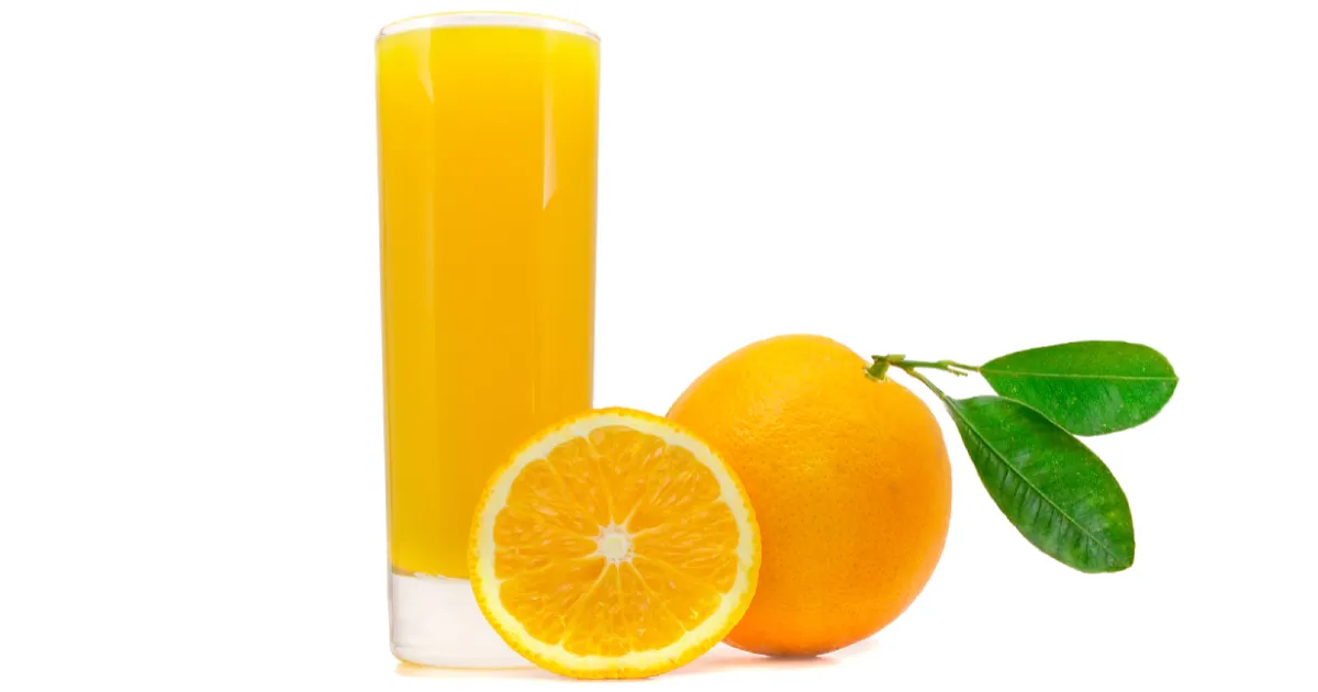 A whole orange next to a glass of fresh orange juice.