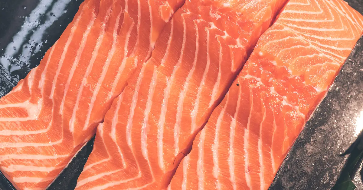 Three raw farmed Atlantic salmon fillets.