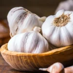 Garlic: Nutrition, Health Benefits, and Downsides Fresh garlic cloves and bulbs in a small bowl.