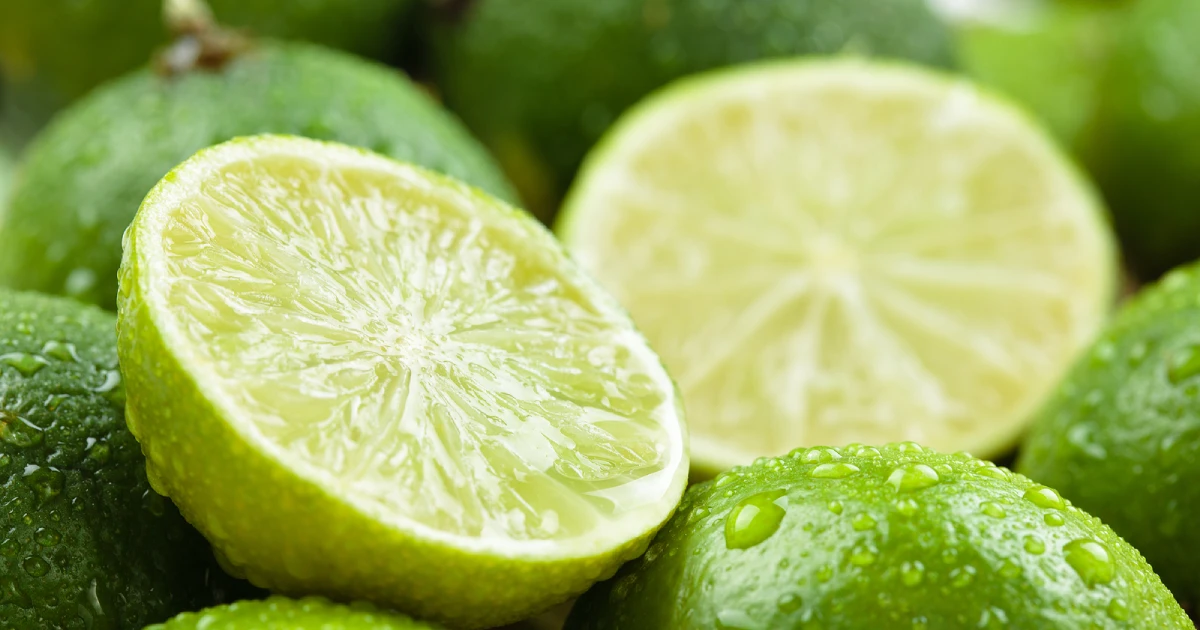 Whole limes and a lime sliced into two halves.