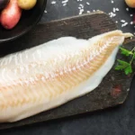 Cod: Nutrition Facts and Potential Health Benefits A white fillet of cod fish on a black wooden board.